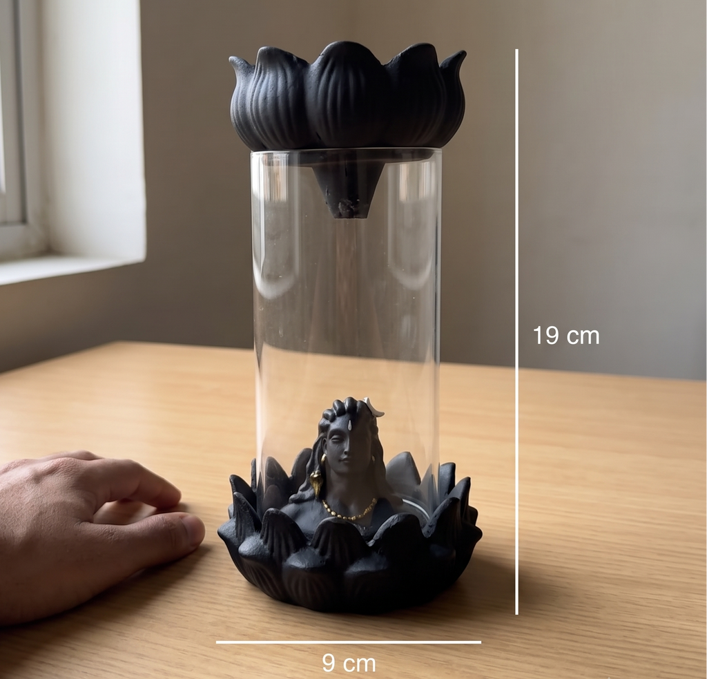 A clear cylindrical glass container with a black lotus-shaped top and base, shown on a wooden table with a hand at left and dimension lines indicating 19 cm height and 9 cm width.